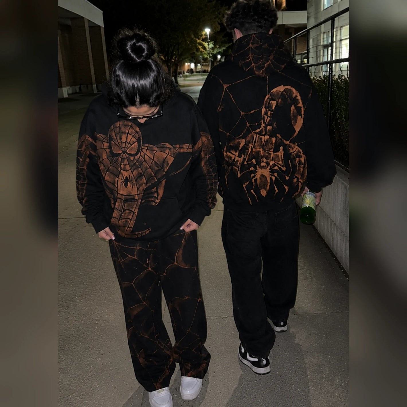 Two people wearing the hoodies outside at night